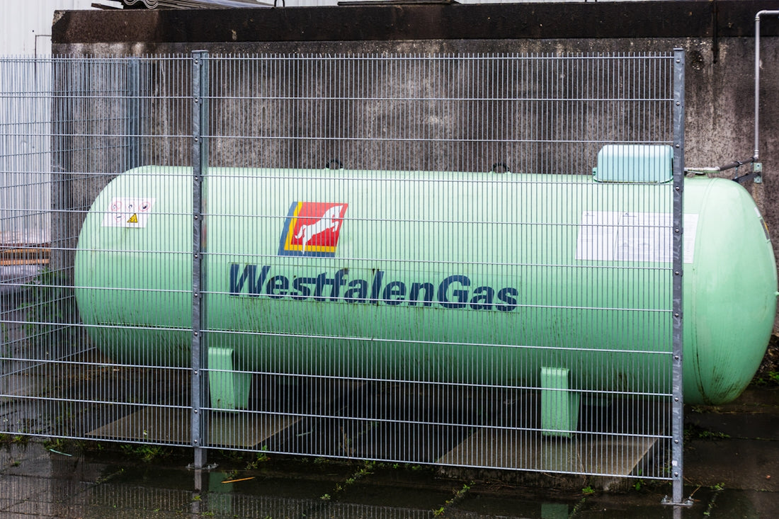 A large green westfalengas storage tank behind a fence